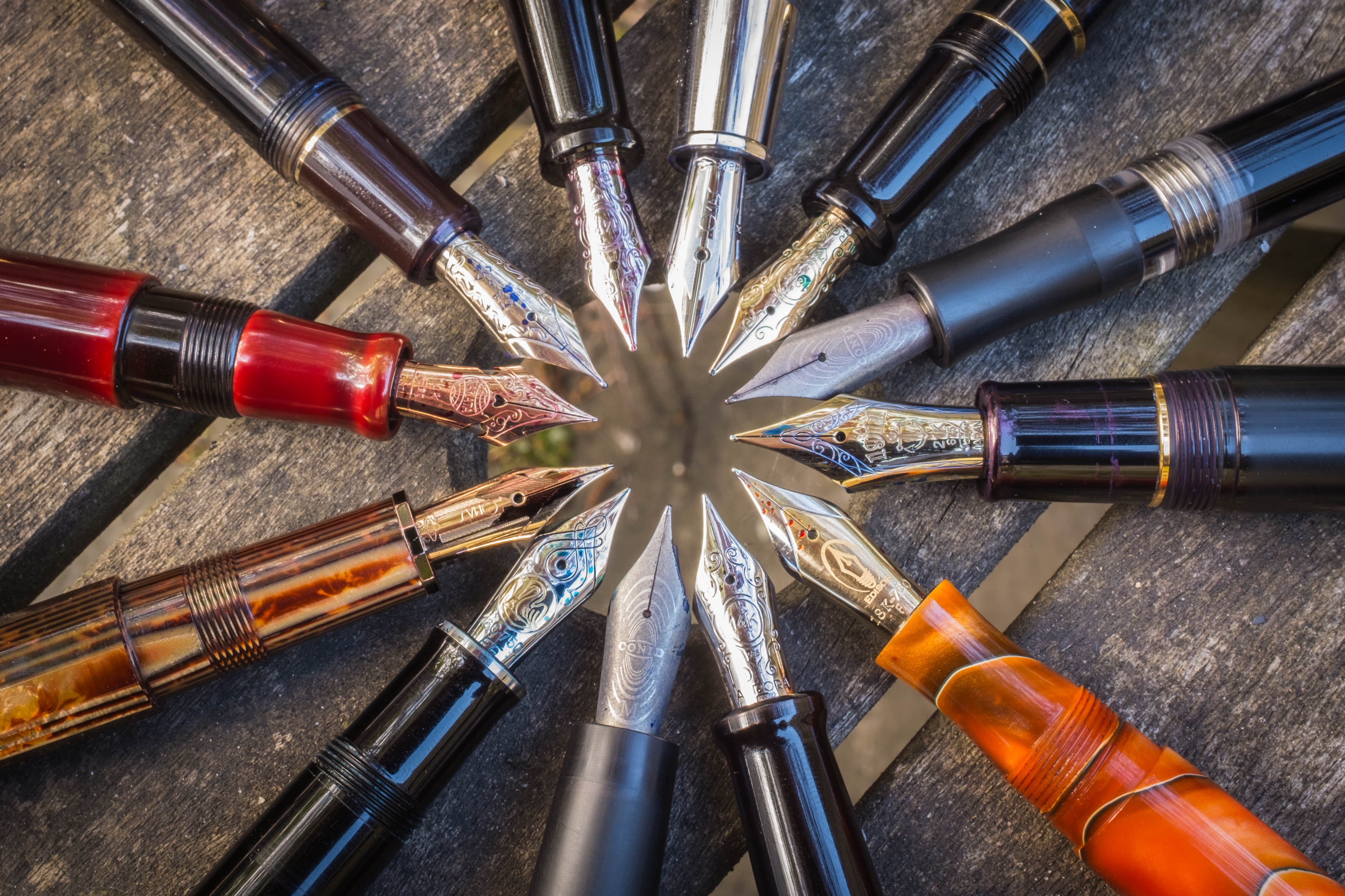 one dozen multicolored fountain pens laid point to point