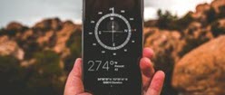 Compass held by hand against rocky background